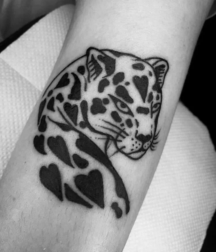 Tatuagem blackwork no antebraço: cabeça de onça com as pintas em formato de coração, em preto sólido