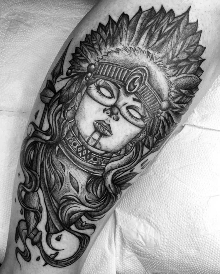 Tatuagem ilustrativa em preto e cinza no braço: retrato de mulher com cocar